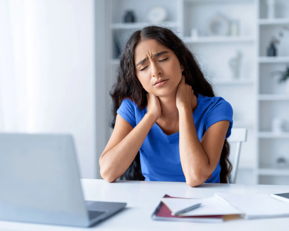 Fatiga crónica Mujer con dolor de cuello frente al portátil.