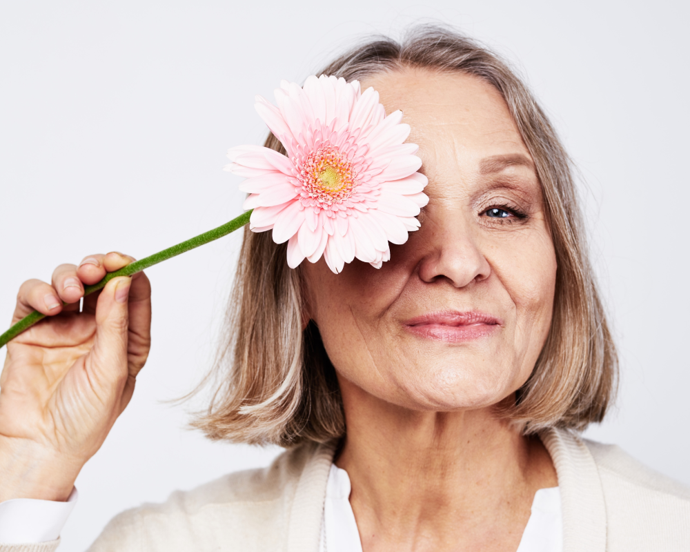 Menopausia Mujer mayor con flor rosada en el ojo