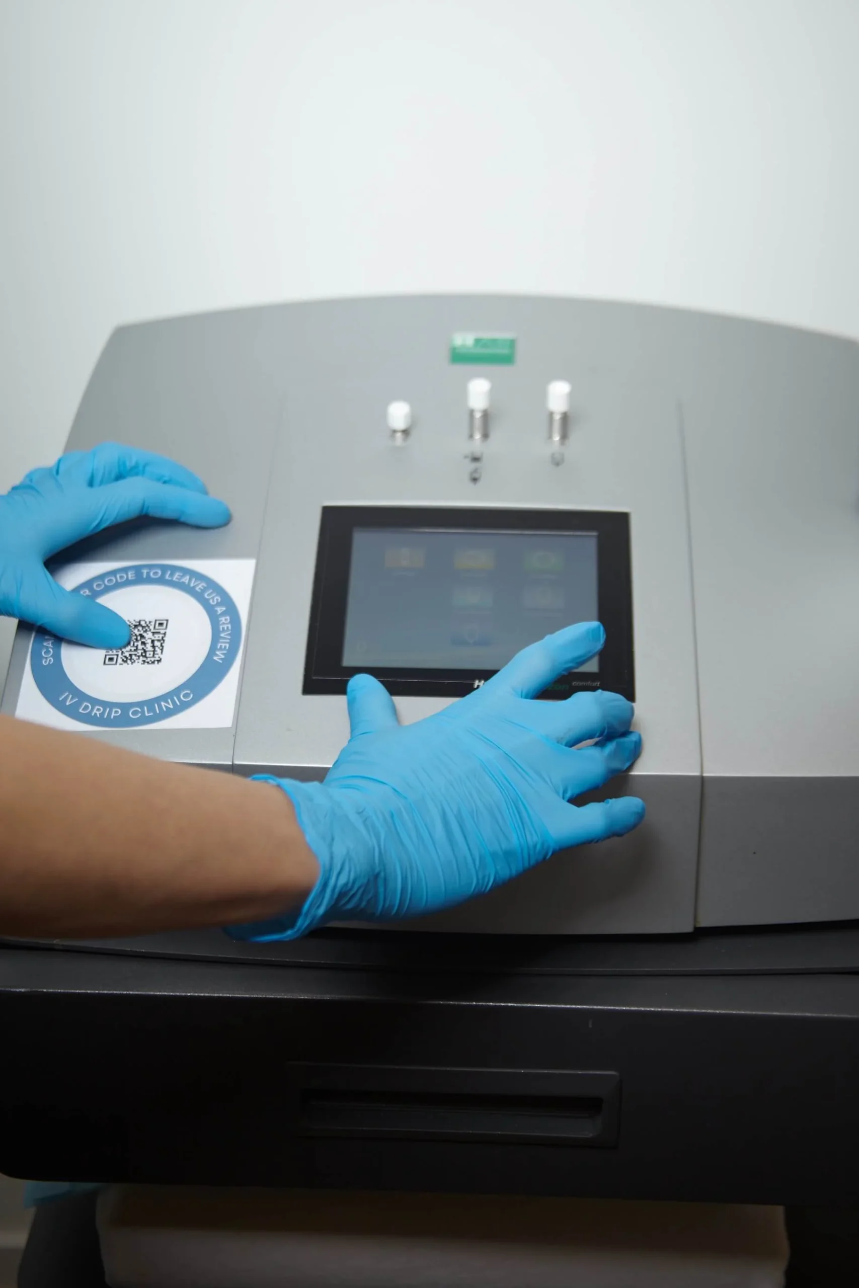 Manos con guantes azules usan máquina médica.